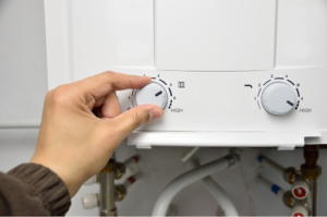 A person adjusting the setting on a tankless water heater.