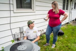 Mike Williams technician looking back at happy homeowner after installing new air conditioner unit in Bloomington, IL home.