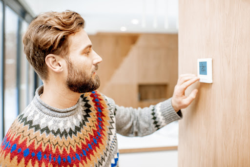 A man adjusting a thermostat in a home.