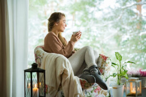 A smiling woman sitting on a couch with a blanket.