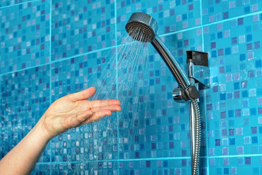 A hand feeling the water pressure in a shower.