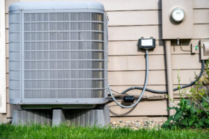An outdoor AC unit installed along the outside of a house.