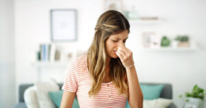 Homeowner holding her nose to prevent smelling sewer gas.