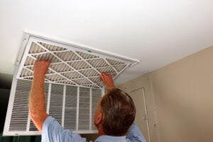 male homeowner changing the air filter on a ceiling register