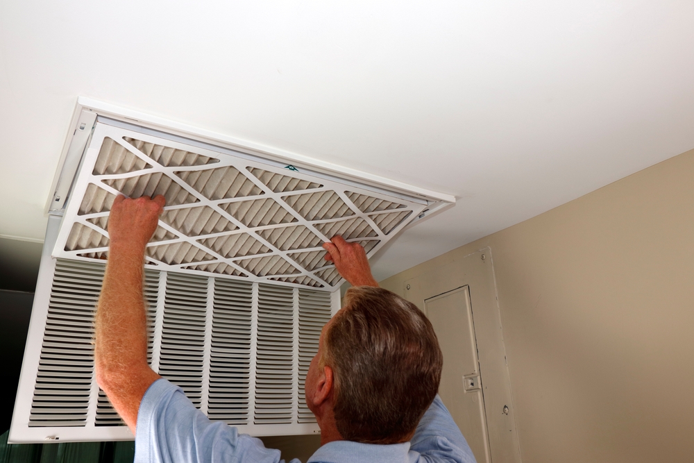 male homeowner changing the air filter on a ceiling register